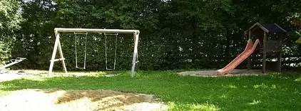 Spielplatz, Gebüsch, Schaukel für zwei Kinder, Rutsche, grüne Wiese