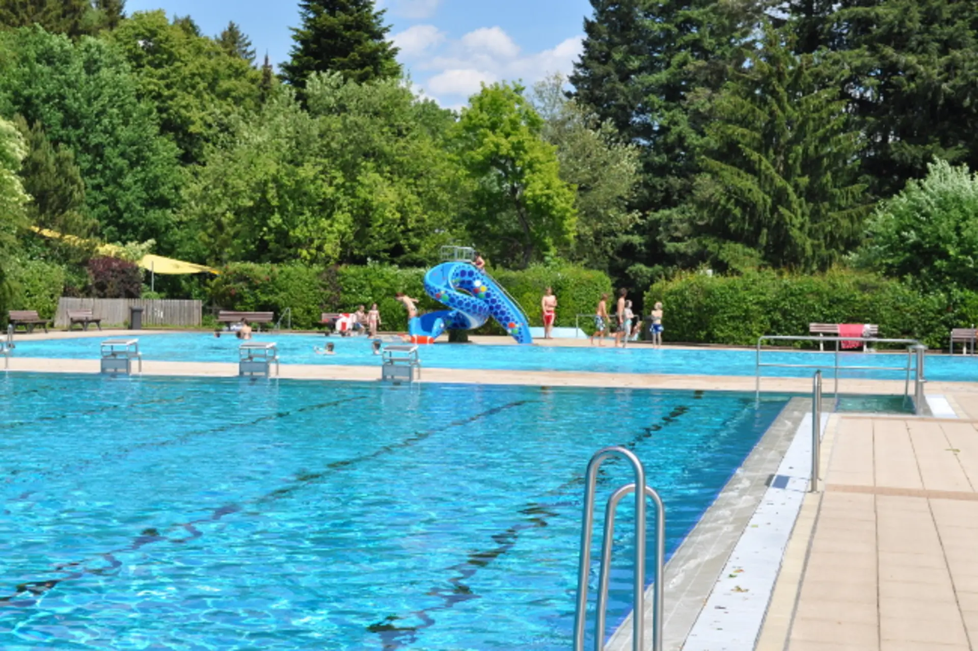 Schwimmerbecken, im Hintergrund ist eine blaue Rutsche zu sehen